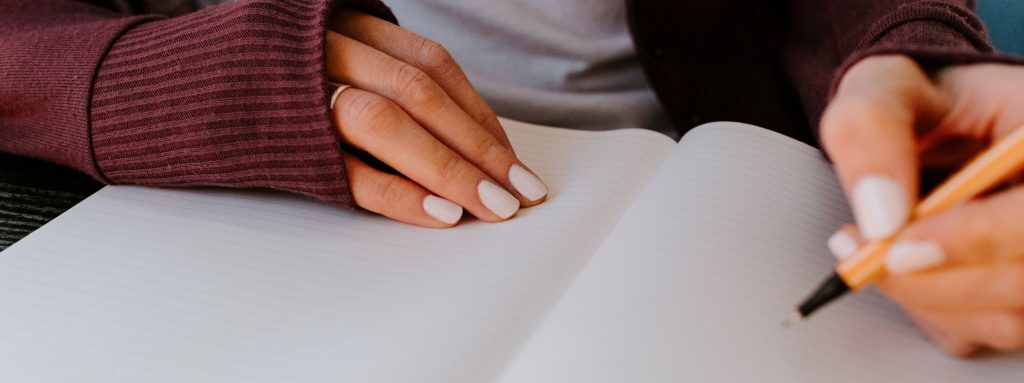Como começar uma redação: imagem de uma pessoa escrevendo em um caderno