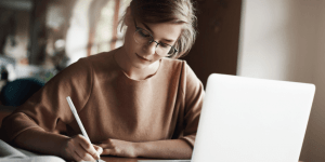 Sites de correção de redação: imagem de uma mulher concentrada escrevendo uma redação